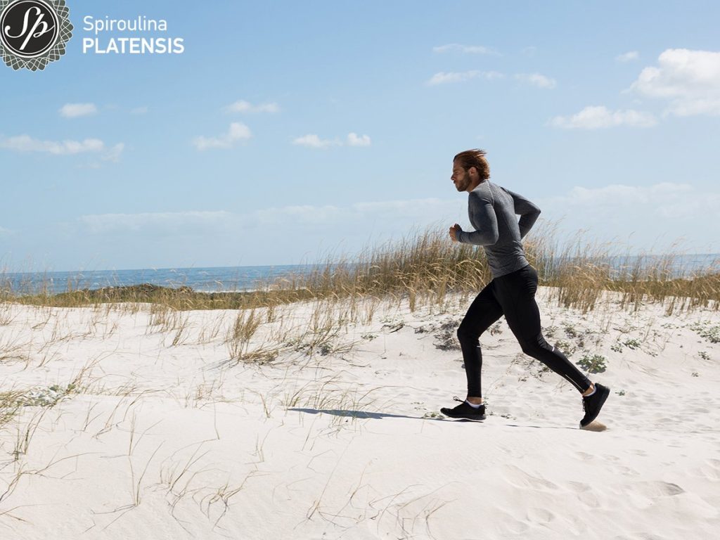 male athlete running beach site