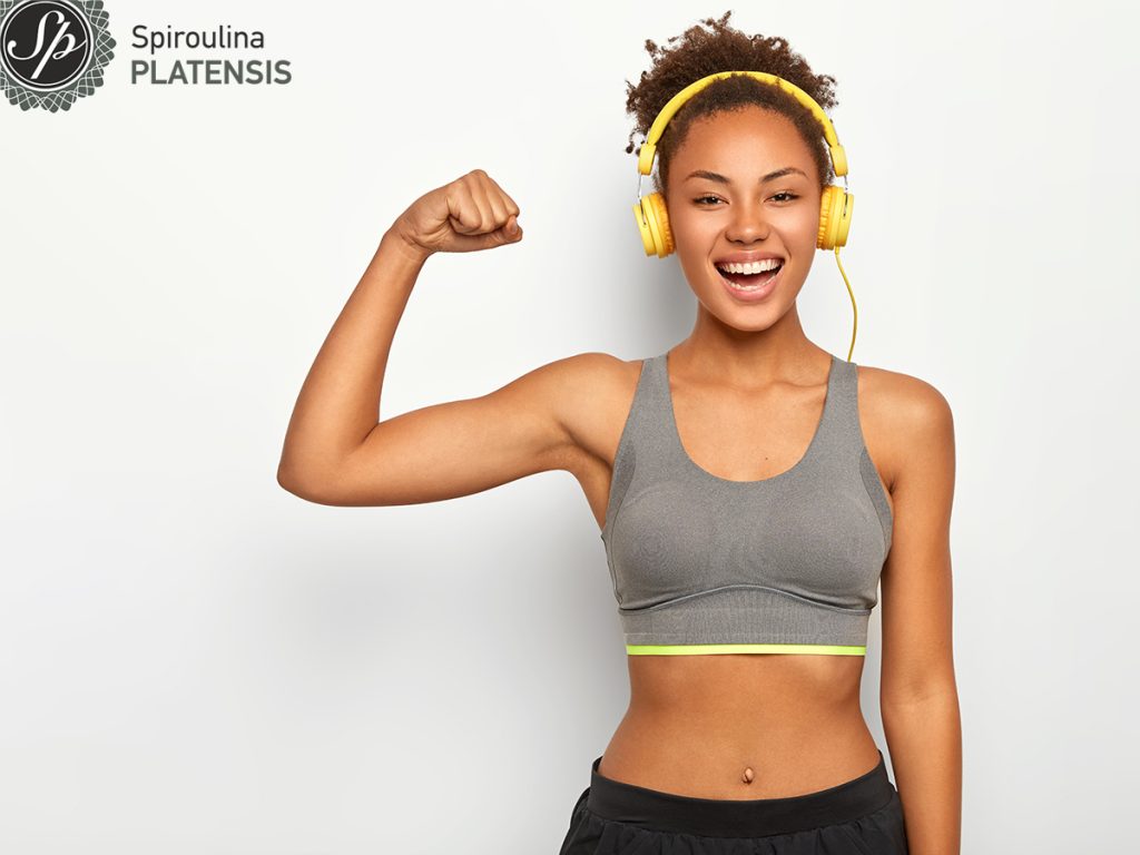 woman good mood raises arm with muscles has strong body dressed gym site